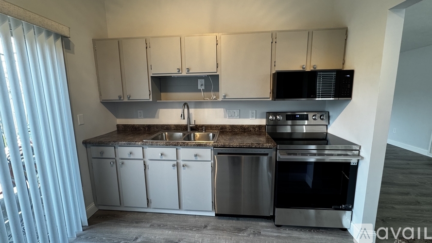 A kitchen with a sink, stove, and cabinets.