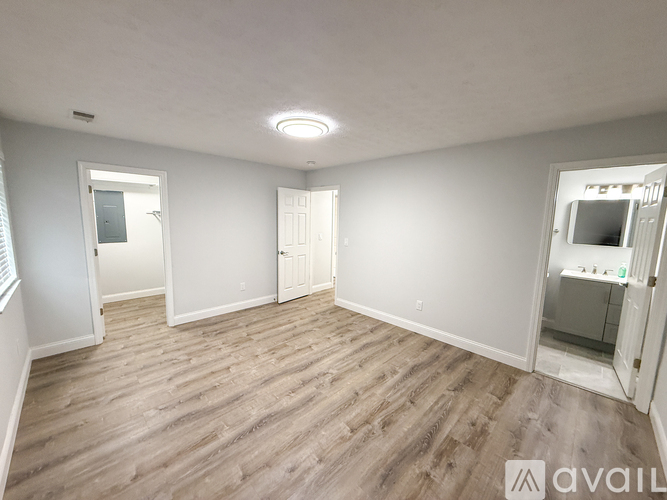 A spacious room with wooden flooring and white walls.