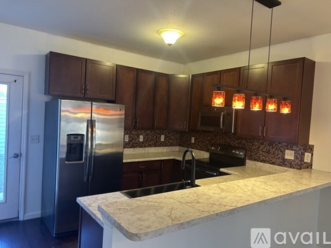 A kitchen with brown cabinets and a stainless steel refrigerator.
