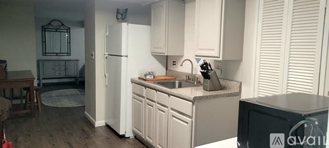 A kitchen with white cabinets and a black fridge.
