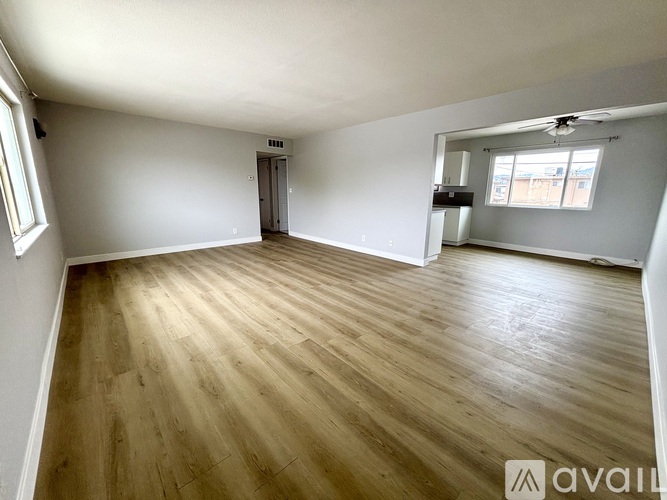 A spacious room with wooden flooring and white walls.