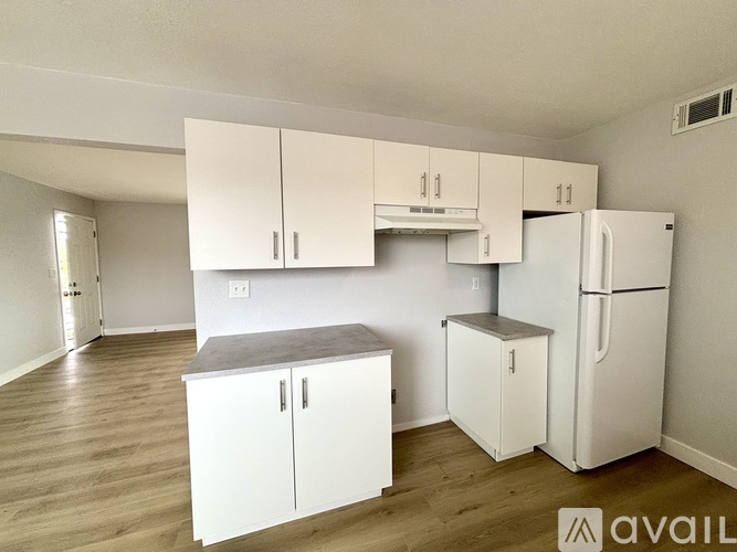 A kitchen with white cabinets and a refrigerator.