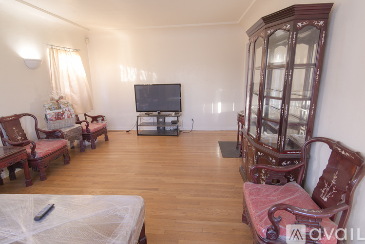 A living room with a television, chairs, and a cabinet.