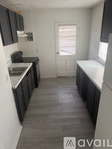 A kitchen with black cabinets and a white door.