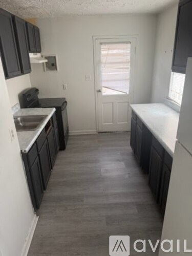 A kitchen with black cabinets and a white door.