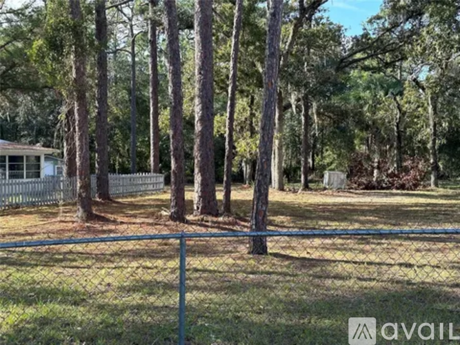 A house is surrounded by a fence and trees.