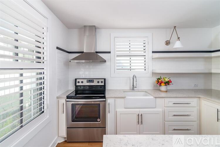 A kitchen with white cabinets and a stove top oven.