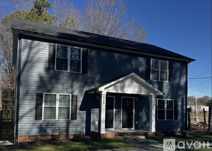 A blue house with a porch and a sign that says "avail" in front of it.