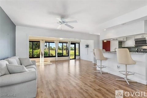 A spacious living room with a grey sofa and a wooden floor.