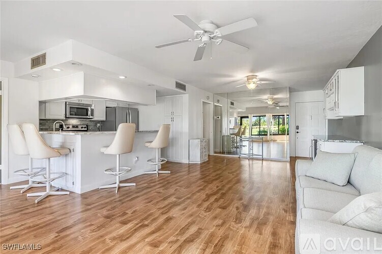 A modern kitchen with white cabinets and a bar area.