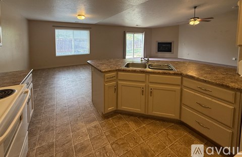 A kitchen with a tile floor and a countertop with a sink and a window.