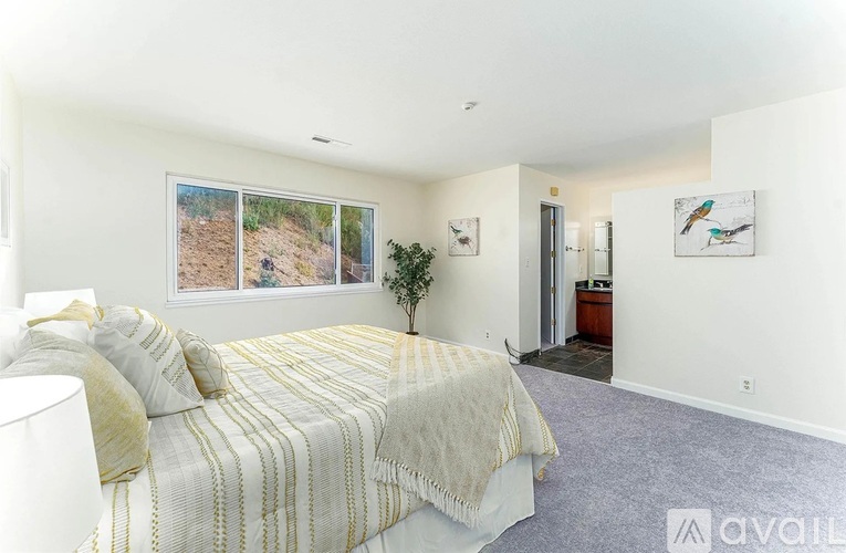 A bedroom with a large bed and a window overlooking a dirt path.
