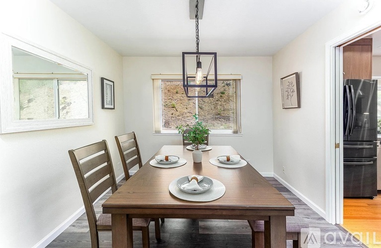 A dining room with a wooden table set for two.