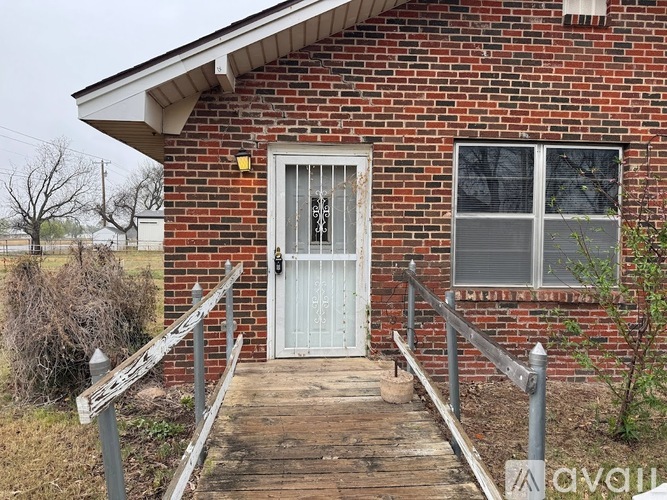 A brick house with a white door and a wooden porch.