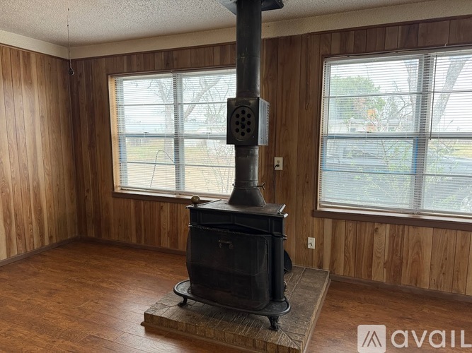 A wood burning stove in a room with wooden walls.