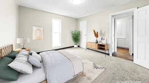 A bedroom with a bed, nightstand, and a potted plant.
