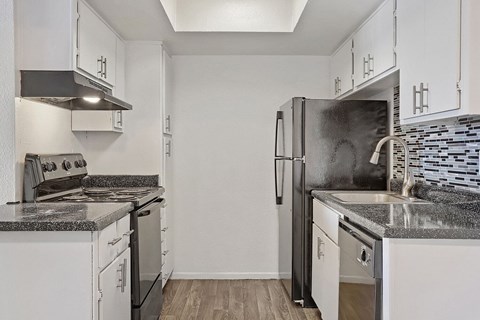 A kitchen with white cabinets and a black refrigerator.