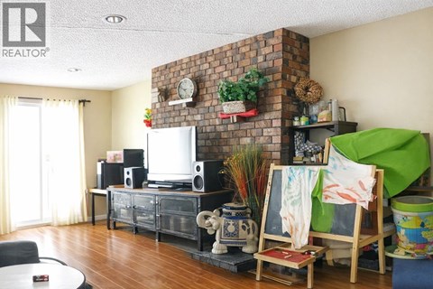 A living room with a brick fireplace and a flat screen TV.