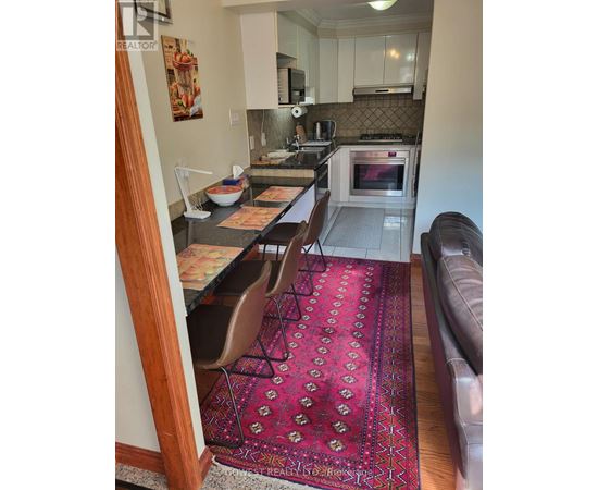 A kitchen with a red rug on the floor.