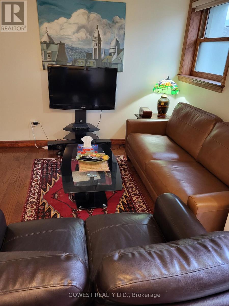A living room with a brown leather couch and a flat screen TV mounted on the wall.