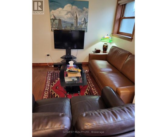 A living room with a brown leather couch and a flat screen TV mounted on the wall.
