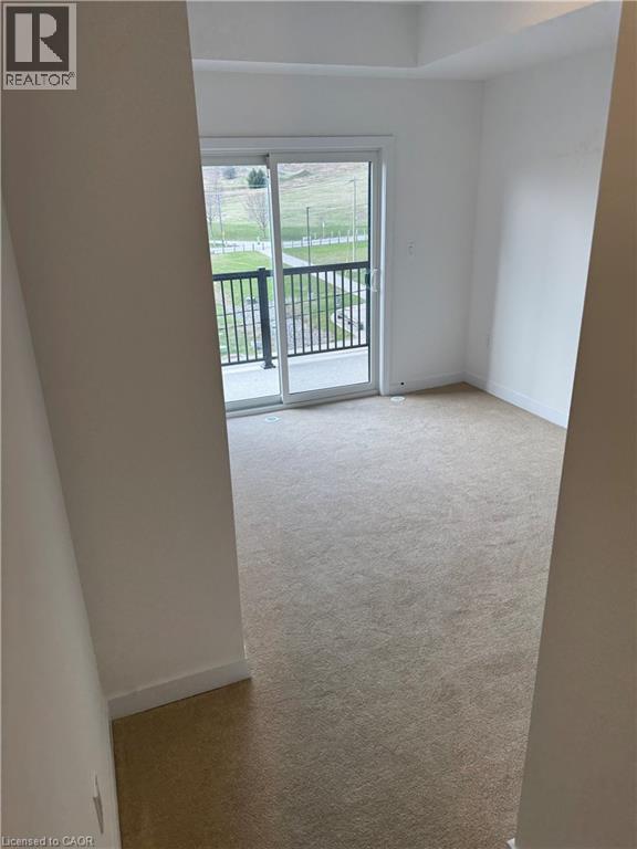 A room with a carpeted floor and a sliding glass door leading to a balcony.