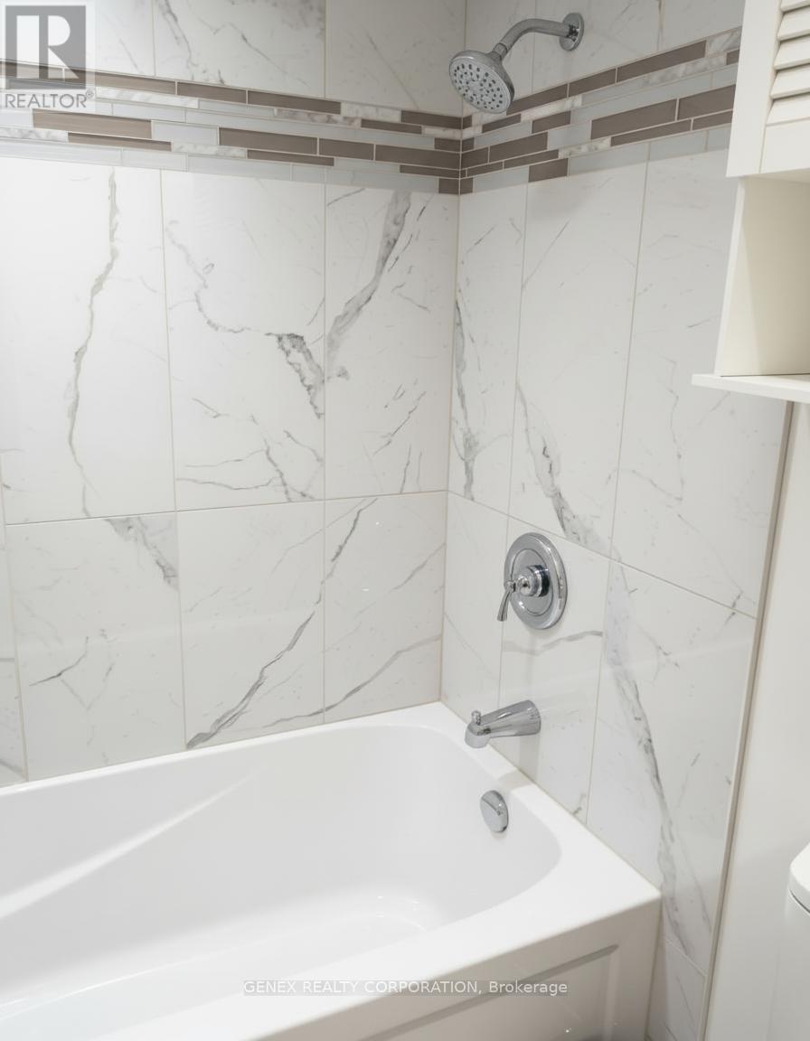 A white marble bathroom with a bathtub and shower head.