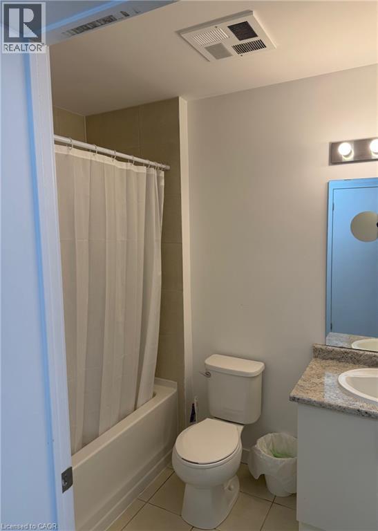 A small white toilet in a bathroom with a white shower curtain.