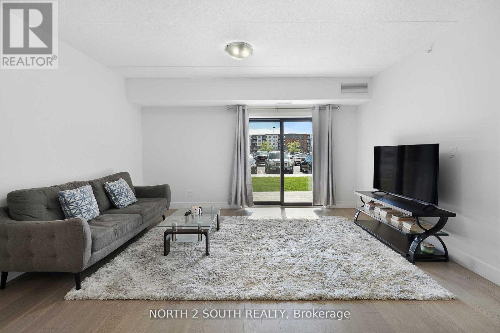 A living room with a grey couch, a coffee table, and a flat screen TV.