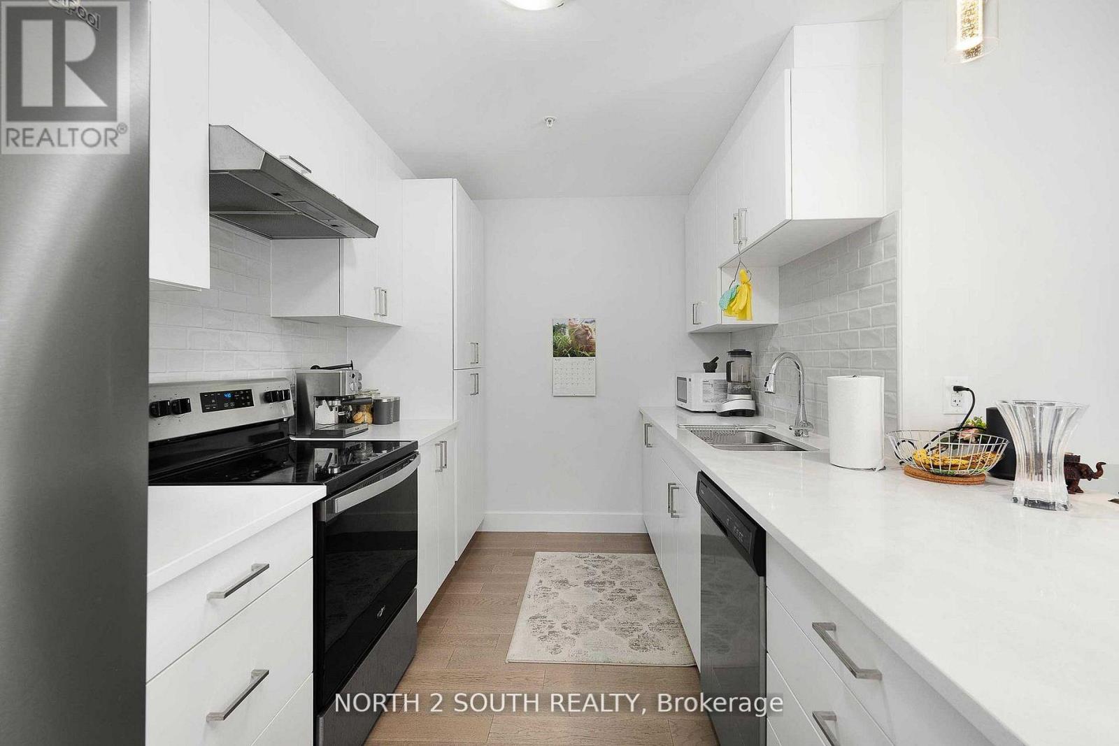 A white kitchen with a black stove top oven and a white fridge.