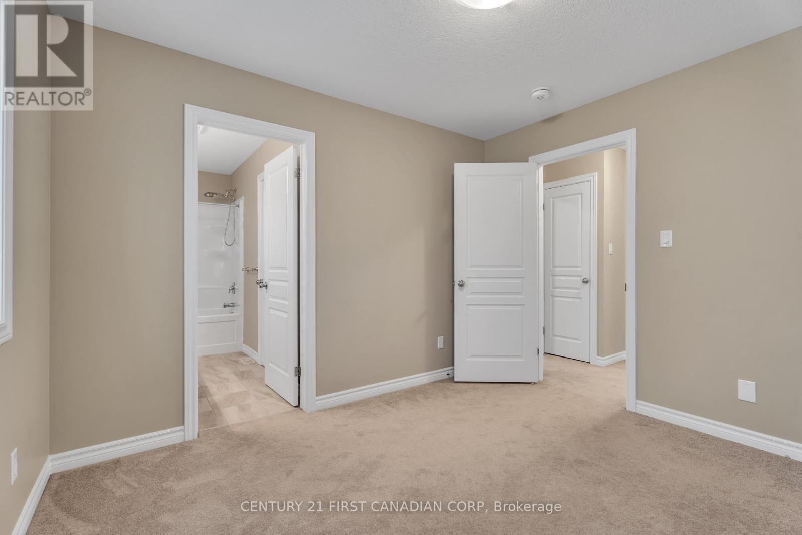 A realtor photo of a bedroom with two doors and a hallway.