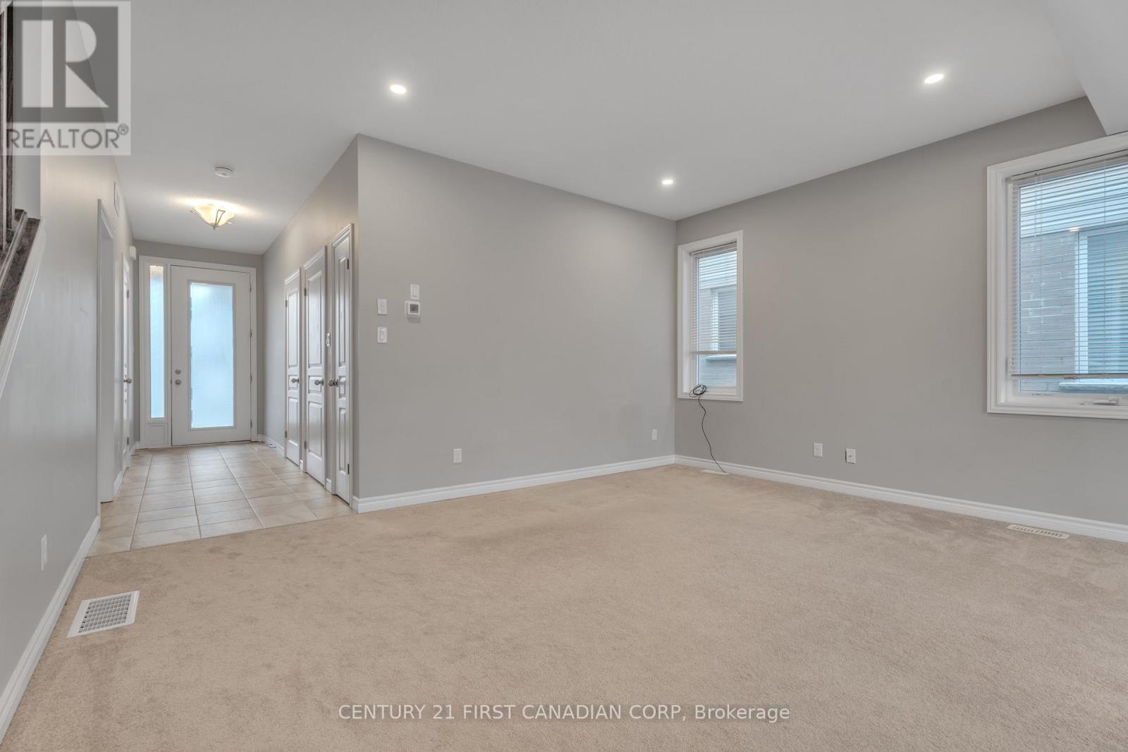 A spacious room with a carpeted floor and a window with blinds.