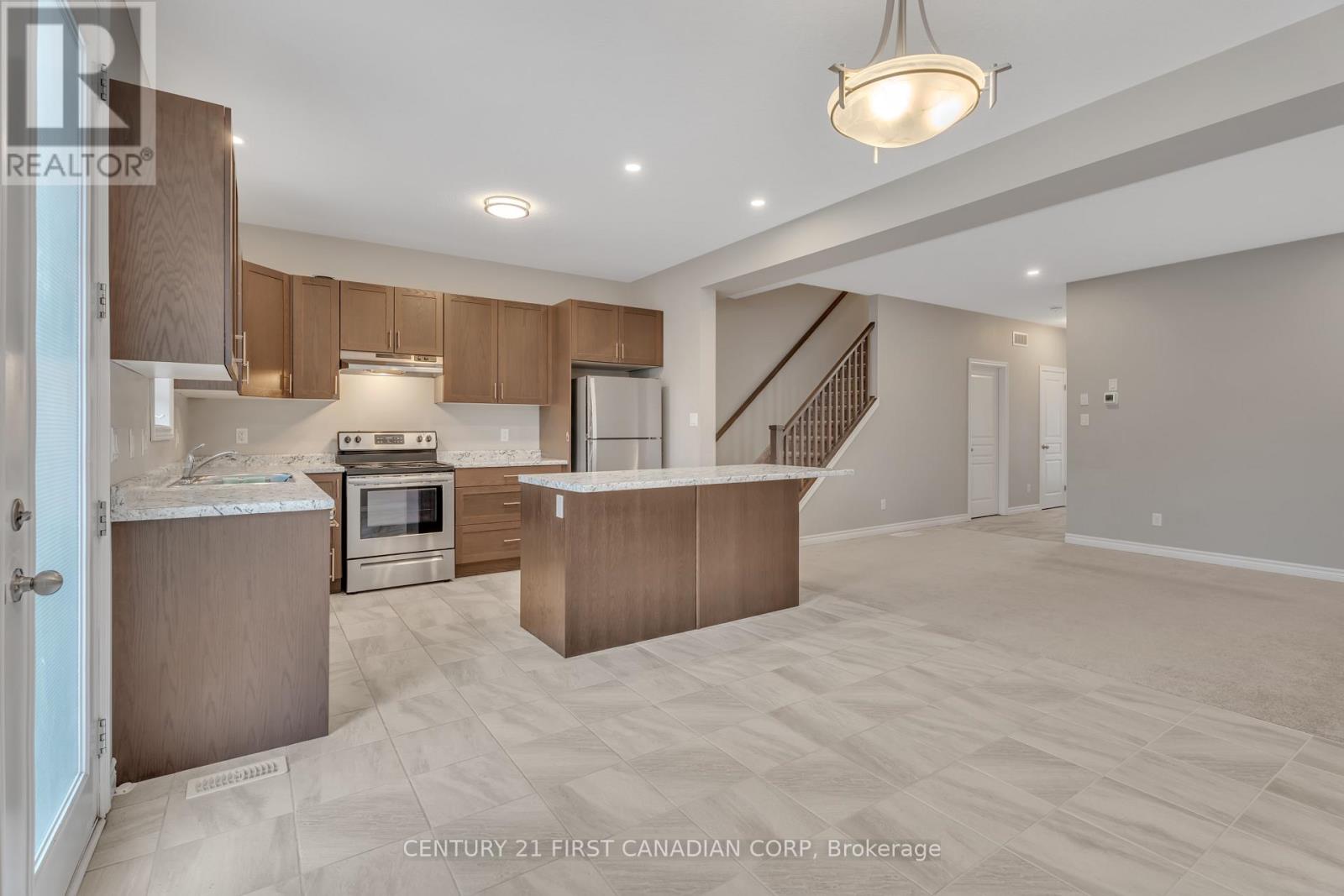 A spacious kitchen and living room with wooden cabinets and a staircase.