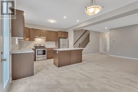 A spacious kitchen and living room with wooden cabinets and a staircase.