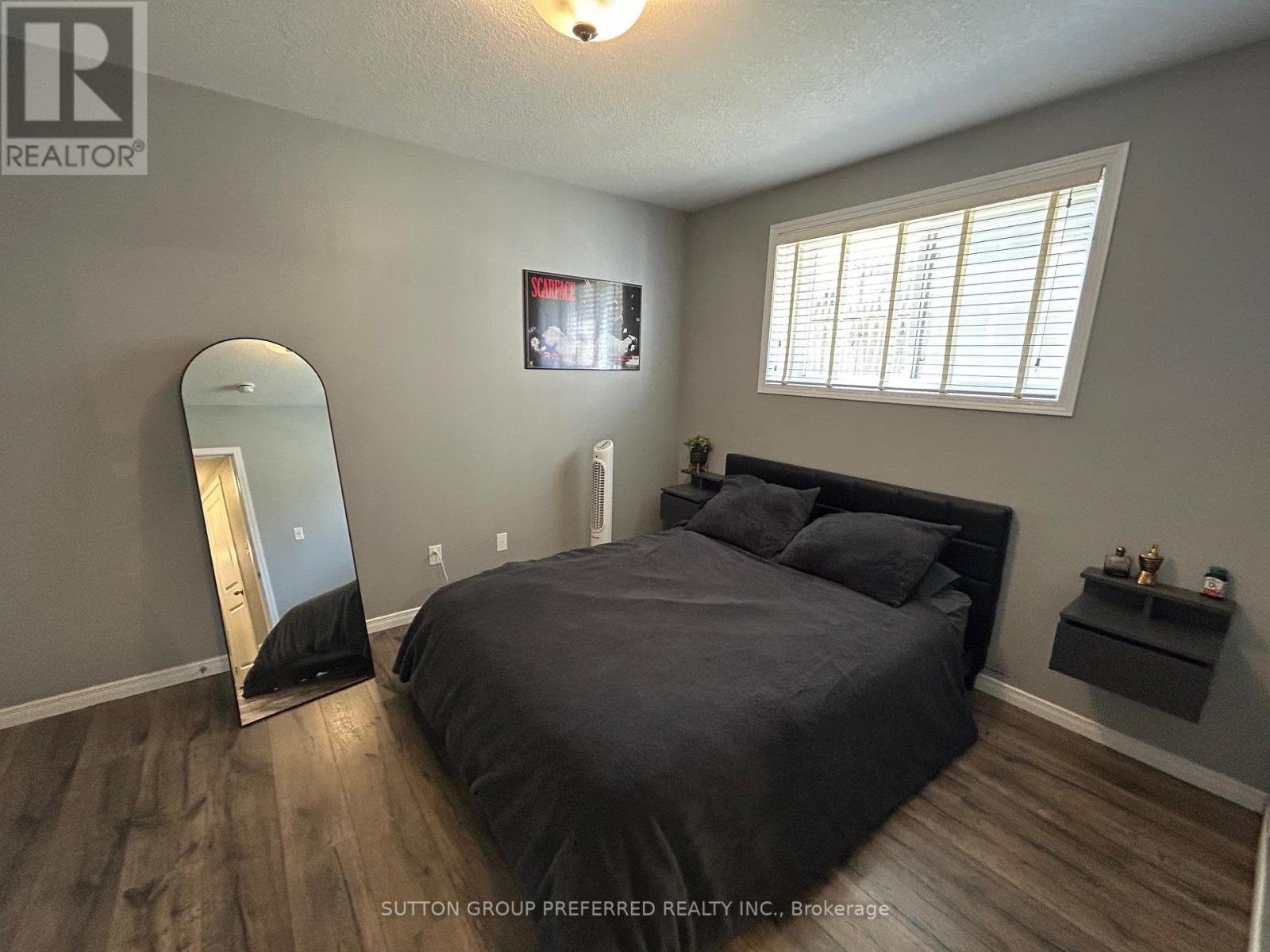 A bedroom with a large bed, a mirror, and a TV mounted on the wall.