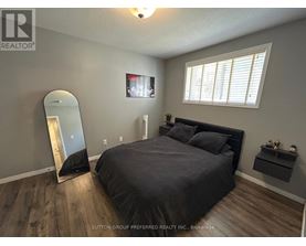 A bedroom with a large bed, a mirror, and a TV mounted on the wall.