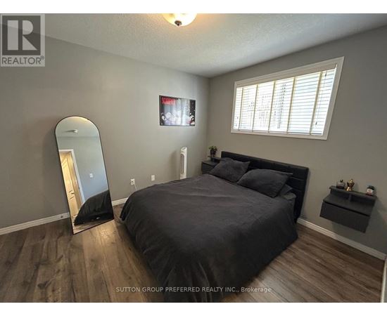 A bedroom with a large bed, a mirror, and a TV mounted on the wall.
