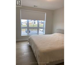 A bedroom with a large bed and a view of a parking lot through the window.