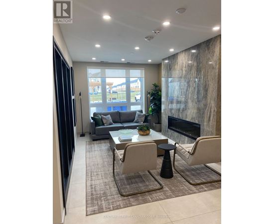 A modern living room with a grey sofa, a black fireplace, and a glass door leading to a balcony.