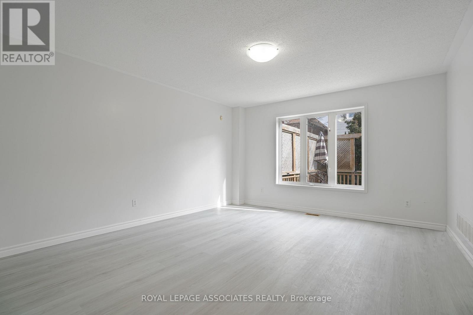 A white room with a window and a wooden floor.