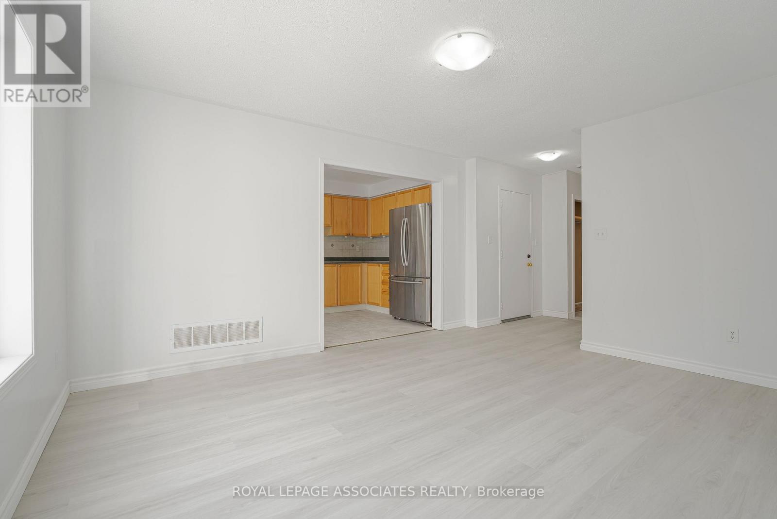 A white room with a wooden floor and a white ceiling with a light fixture.