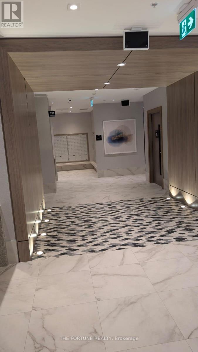 A hallway with a marble floor and a green exit sign.