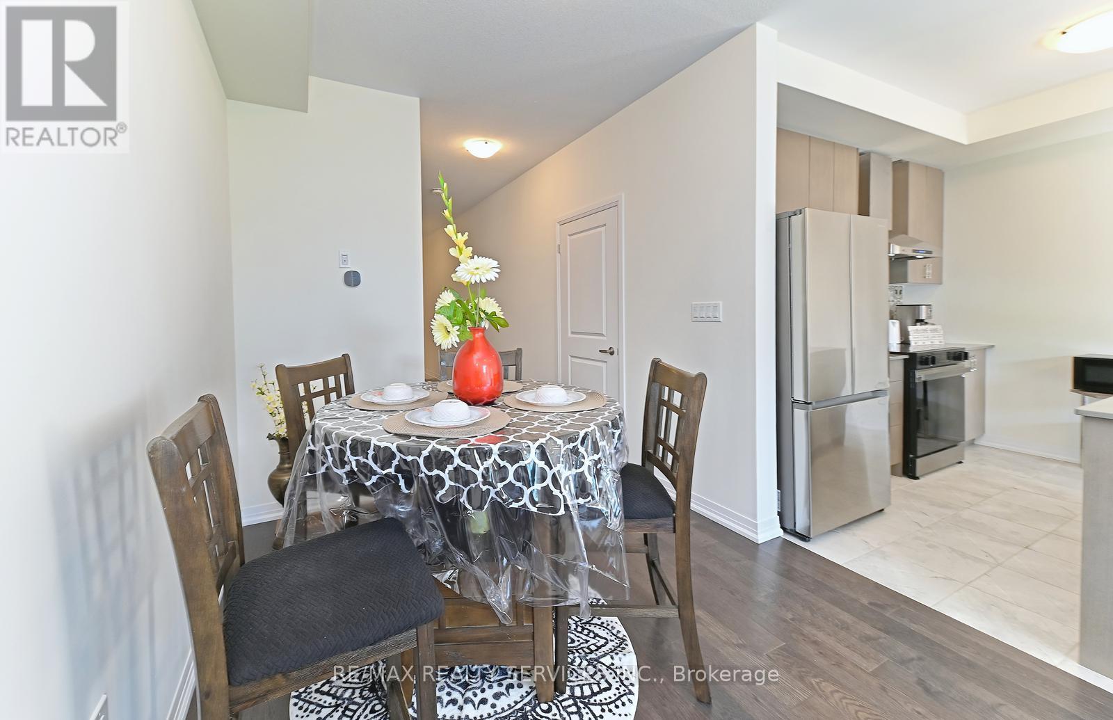A dining room with a table set for two and a refrigerator in the background.