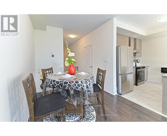 A dining room with a table set for two and a refrigerator in the background.