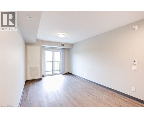 A spacious room with a sliding glass door leading to a balcony.