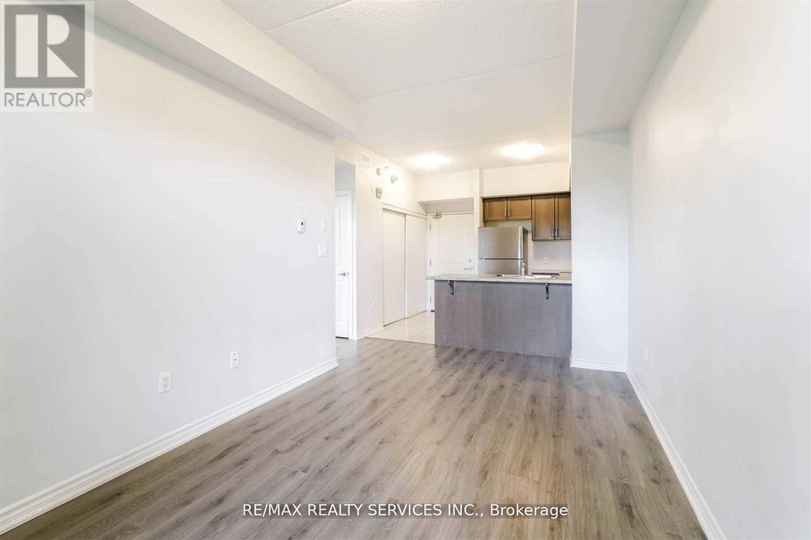 A room with a wooden floor and a white wall with a door on the left side.
