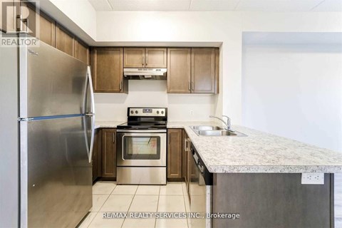 A kitchen with a refrigerator, oven, and sink.