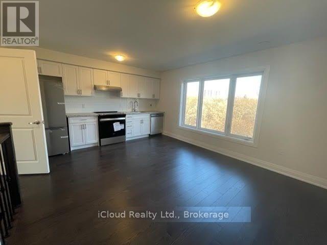 A spacious kitchen and living room with hardwood floors and white walls.