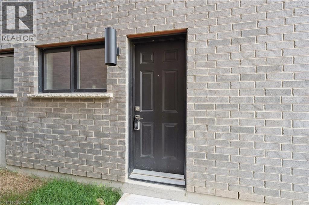 A grey brick house with a brown door and a window.