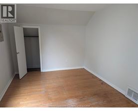 A room with wooden floors and white walls, with a doorway leading to another room.